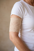 Skin tone lace cover worn on a clothed model's upper arm